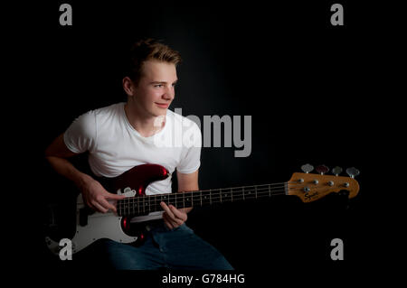 A teenage boy practices his bass guitar Stock Photo