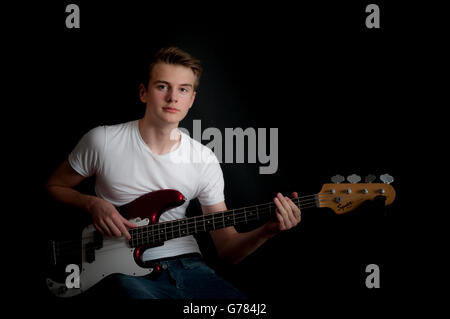 A teenage boy practices his bass guitar Stock Photo