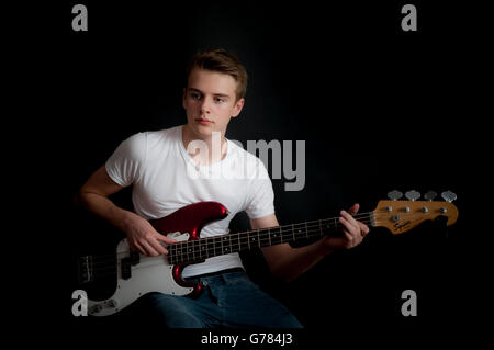 A teenage boy practices his bass guitar Stock Photo