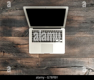 Laptop notebook with black screen on wooden table desk. Office workspace background. German lettering Stock Photo