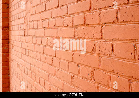 Angle view of a brick wall with a layer of red paint with blurred long-range plan to use as a background. Stock Photo