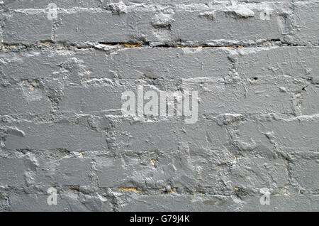 Detail of a brick wall close-up, smeared with cement and painted over with a thick layer of gray paint for use as a background. Stock Photo