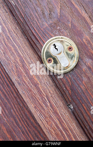 Fragment of a wooden door brown close-up with a keyhole brass diagonal frame. Selective focus. Stock Photo