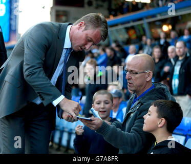 Birmingham City manager Lee Clark signs an autograph for a young fan as he makes his way to the dugout Stock Photo