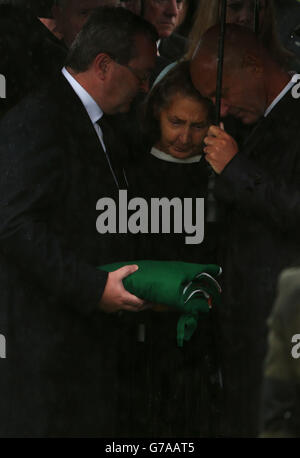 ALTERNATE CROP. Wife of former Taoiseach Albert Reynolds Kathleen Reynolds receives the tricolor from his coffin flanked by two sons Albert (left) and Philip (right) at Shanganagh Cemetery in Shankill, Dublin, for his internment following his funeral service at Church of the Sacred Heart in Donnybrook. Stock Photo