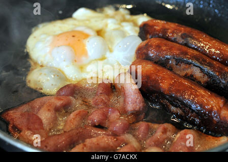 Egg, sausages and bacon being fried in a frying pan. Stock Photo
