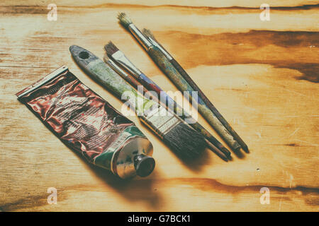 Photograph of a paint tube and some art brushes on a wood table Stock Photo