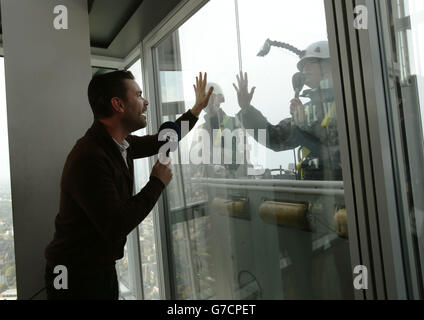 Capital Breakfast presenter Dave Berry speaking to his co-host Lisa Snowdon while she washes the viewing gallery windows after losing an on-air fundraising challenge during a live broadcast from the Shard, in London, as part of Global's Make Some Noise, radio's biggest ever charity appeal. Stock Photo