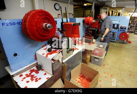 A worker uses a machine for cutting out silk poppies at The Poppy Factory in Richmond, Surrey, where for over 90 years they have been making poppies, crosses and wreaths for the Royal Family and the Royal British Legion's Poppy Appeal. Stock Photo