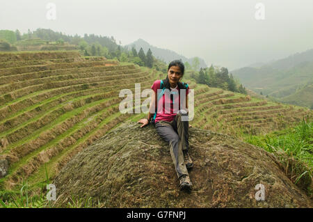 Trekker taking a break by the rice terraces of Jinkeng in Longji, Guangxi Autonomous Region, China Stock Photo