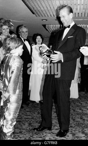 A model of astronaut apparatus is handed to an amused Duke of Edinburgh by space-suited seven-year-old Sascha Auerback, at the Odeon, Leicester Square, London, just before the Royal World Charity Premiere of the latest 007 Bond film, 'Moonraker'. *Scanned low-res from print, high-res available on request* Stock Photo