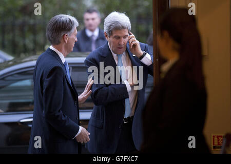 US Secretary of State John Kerry (right) speaks on his phone as he arrives for a breakfast meeting with Foreign Secretary Philip Hammond (left) at 1 Carlton Gardens in London. Stock Photo