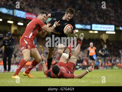 New Zealand's captain Richie McCaw (centre) attempts to evade tackles from Wales' Mike Phillips (left) and Taulupe Faletau during the Dove Men Series match at the Millennium Stadium, Cardiff. Stock Photo