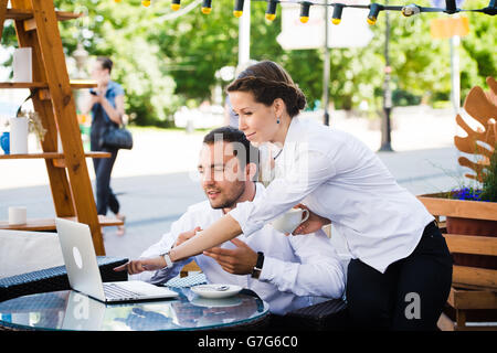 man and woman working on laptop at outdoors cafe during the break Stock Photo