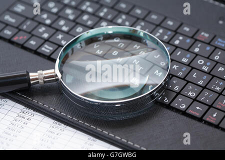 Business concept. Magnifying glass on black laptop keyboard Stock Photo