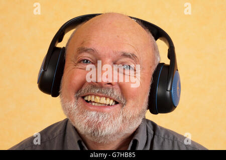 Elderly man, 59, with headphones, laughing Stock Photo