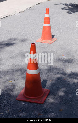 Traffic cone, with white and orange stripes on road. Stock Photo