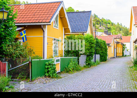 Soderkoping, Sweden - June 19, 2016: Lovely narrow street with granite blocks as pavement. Old fashioned houses along the street Stock Photo
