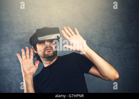 Scared adult man wearing virtual reality goggles and enjoying in scary 3D VR multimedia content Stock Photo