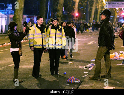 A man wearing a helmet borrowed from a police officer has his picture taken on Victoria Embankment after the fireworks display over the London Eye, in central London, during the New Year celebrations. Stock Photo