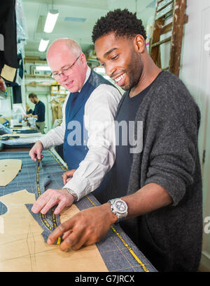 EDITORIAL USE ONLY London Collections: Men Ambassador Tinie Tempah has a final fitting with head cutter Stephen Allen at Savile Row tailors, Norton and Sons in London, for a bespoke suit made from specially commissioned London Tweed designed by the Museum of London, ahead of the Autumn/Winter 2015 menswear fashion shows &ETH; which begins on Friday 9 January. Stock Photo