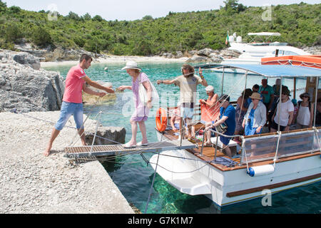 elderly female passenger being helped off tourist cruise boat on the tiny island of AntiPaxos, Greece on a day trip from Paxos Stock Photo
