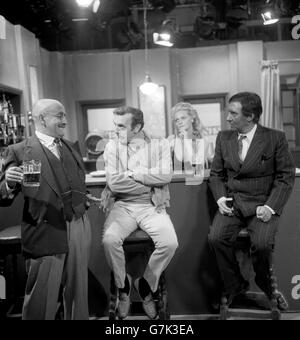 A bald Alf Garnett (Warren Mitchell) with The Foreman (Eric Sykes) and right Paki-Paddy (Spike Milligan) in a discussion on the election campaign during rehearsals for the 25-minute BBC One show called 'Up The Polls', which will be broadcast after the polls close at 10pm. Listening in to the discussion is actress Lorna Wile, who plays a barmaid. Stock Photo