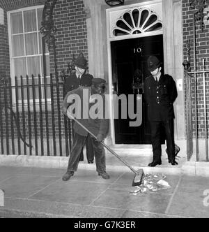 Policemen look on as a road sweeper cleans the pavement outside No 10 Downing Street, London, where the new Prime Minister, Harold Wilson, was working on further names for Ministerial appointments. Stock Photo