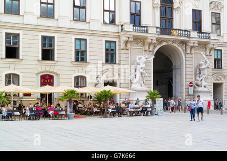 People on terrace of outdoor cafe and Michael's Gate, In der burg square, Imperial Palace Hofburg in Vienna, Austria Stock Photo