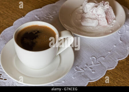 White cup of turkish coffee and small plate of lokum on wooden table Stock Photo