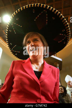 First Minister Nicola Sturgeon tries on a Sombrero next to Luis Garcia from Mexico as she attends the National Mass at St Columbkilles RC Church in Glasgow to celebrate the 50th anniversary of the Scottish Catholic International Aid Fund and to mark the life-changing work of the charity Stock Photo