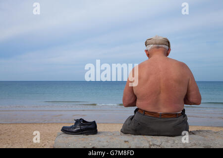 Old man sitting alone at the beach Stock Photo