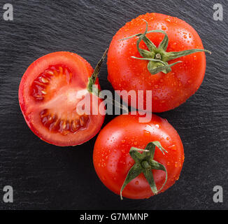tomatoes with water drops on a slate table. Stock Photo