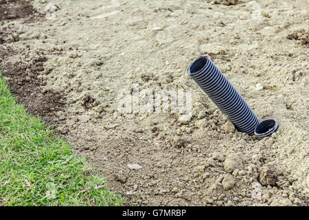 Black plastic corrugated pipes are coming out from the ground. Stock Photo