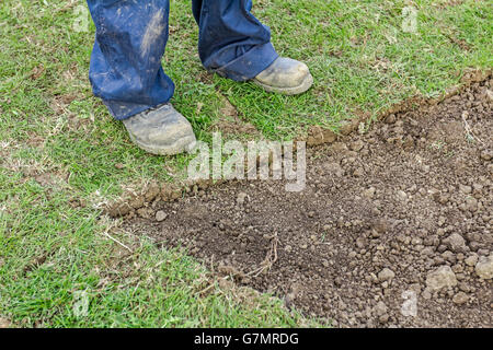 Worker in safety shoes is standing on new garden lawn at a residential construction site. Stock Photo