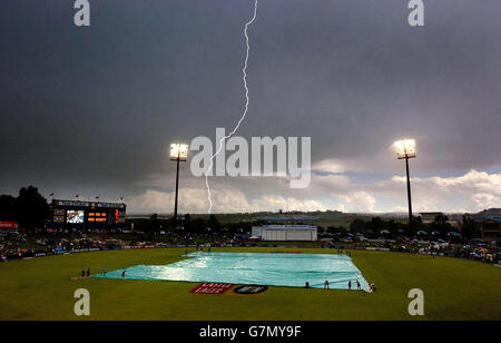 A lightning bolt flashes as ground staff cover the pitch. Stock Photo