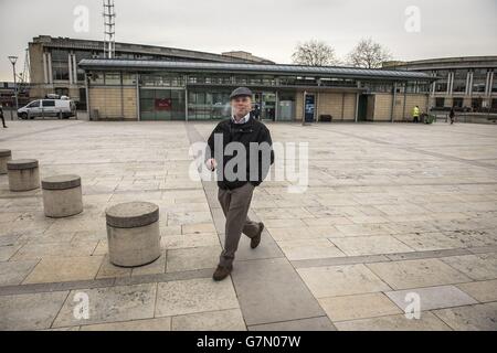A man smokes a cigarette whilst walking through Millennium Square in Bristol, as it is one of the two public spaces to go smokefree as a voluntary pilot is launched. Stock Photo