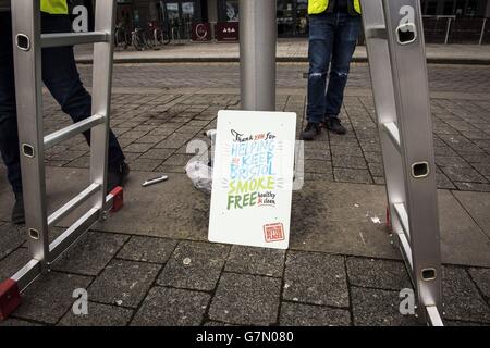 A sign next to a lamp post in Millennium Square in Bristol, as it is one of the two public spaces to go smokefree as a voluntary pilot is launched. Stock Photo
