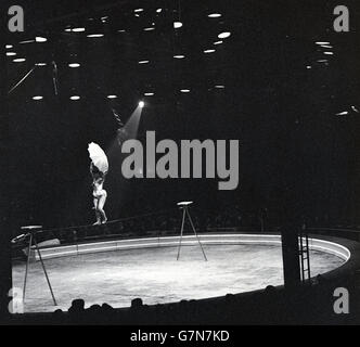 1950s, historical picture of a female trapeze artist performing under lights at a circus. Stock Photo