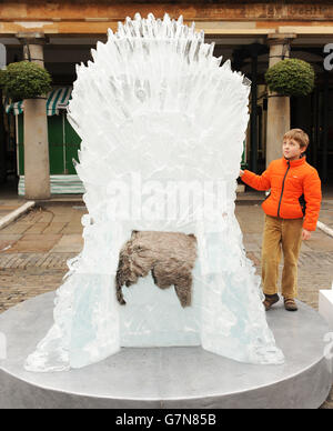 Eight-year-old Ben Finn looks at an ice sculpted, life-sized, Iron Throne which is on display in Covent Garden, London, to celebrate the launch of Game of Thrones: The Complete Fourth Season. Stock Photo