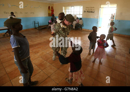 Lance Corporal Amy Sutherland plays with children, as soldiers from 2 Scots, visit the Nanyuki Children's Home to donate gifts to the orphaned children as soldiers from the 2nd Battalion, The Royal Regiment of Scotland, take part in Exercise Askari Storm on the outskirts of Nanyuki, Kenya. Stock Photo