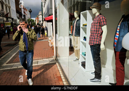 Man walking on Grafton Street while smoking a cigarette and telephoning in Dublin, Ireland Stock Photo