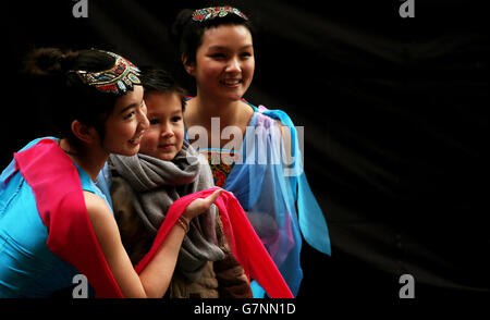 Performers from the Chinese Irish Culture Academy Ciara Liu (left) and Christina Chan pose for a photograph with six year old Patrick Sweeney from Gorey, as they wait to take to the stage during the Chinese New Year Carnival Experience in Dublin's City centre. Stock Photo