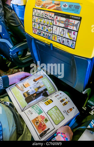 A female passenger looks through the Ryanair in-flight catalogue on board a plane. Stock Photo