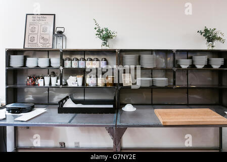 Metal shelves in the breakfast room of a hotel with cutlery, plates, bowls etc. Stock Photo