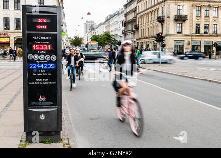 Cyclists in Copenhagen, Denmark, cycle past a sign which counds the number of cyclists per day/year passing this point. Stock Photo