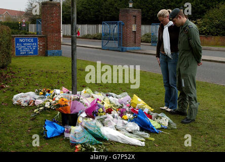 A couple bow their heads for a moment after laying flowers at the main gate of RAF Lyneham. Stock Photo