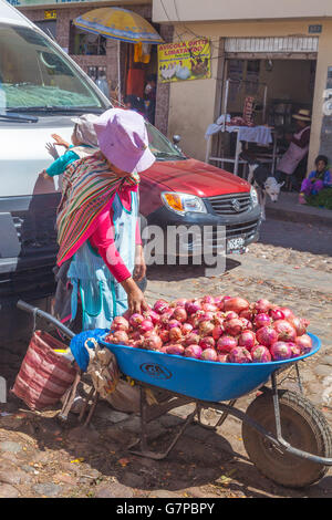 Mother and child selling red onions from a wheelbarrow at the San Pedro market in Cusco, Peru Stock Photo