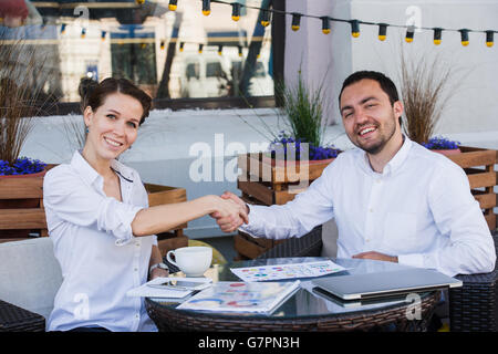 Young business people shake their hands in summer cafe Stock Photo