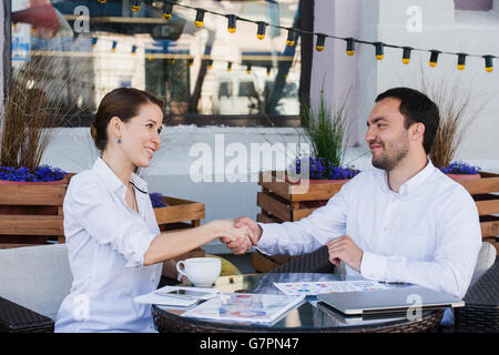 Young business people shake their hands in summer cafe Stock Photo